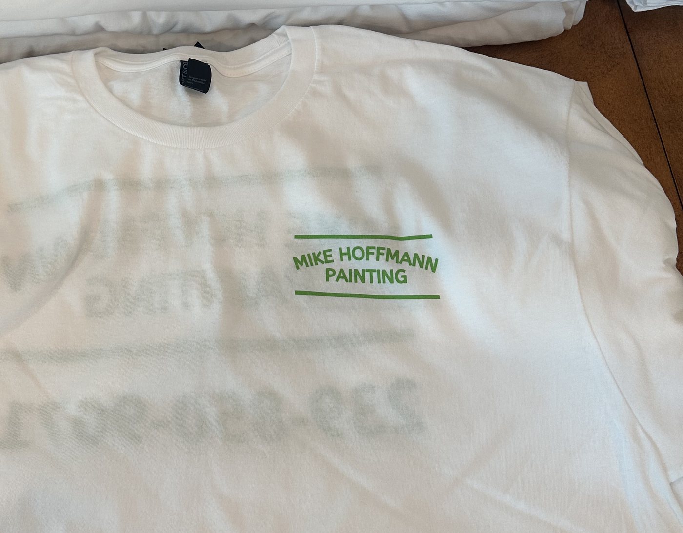 Stacks of white work tees with a 1-color green company logo