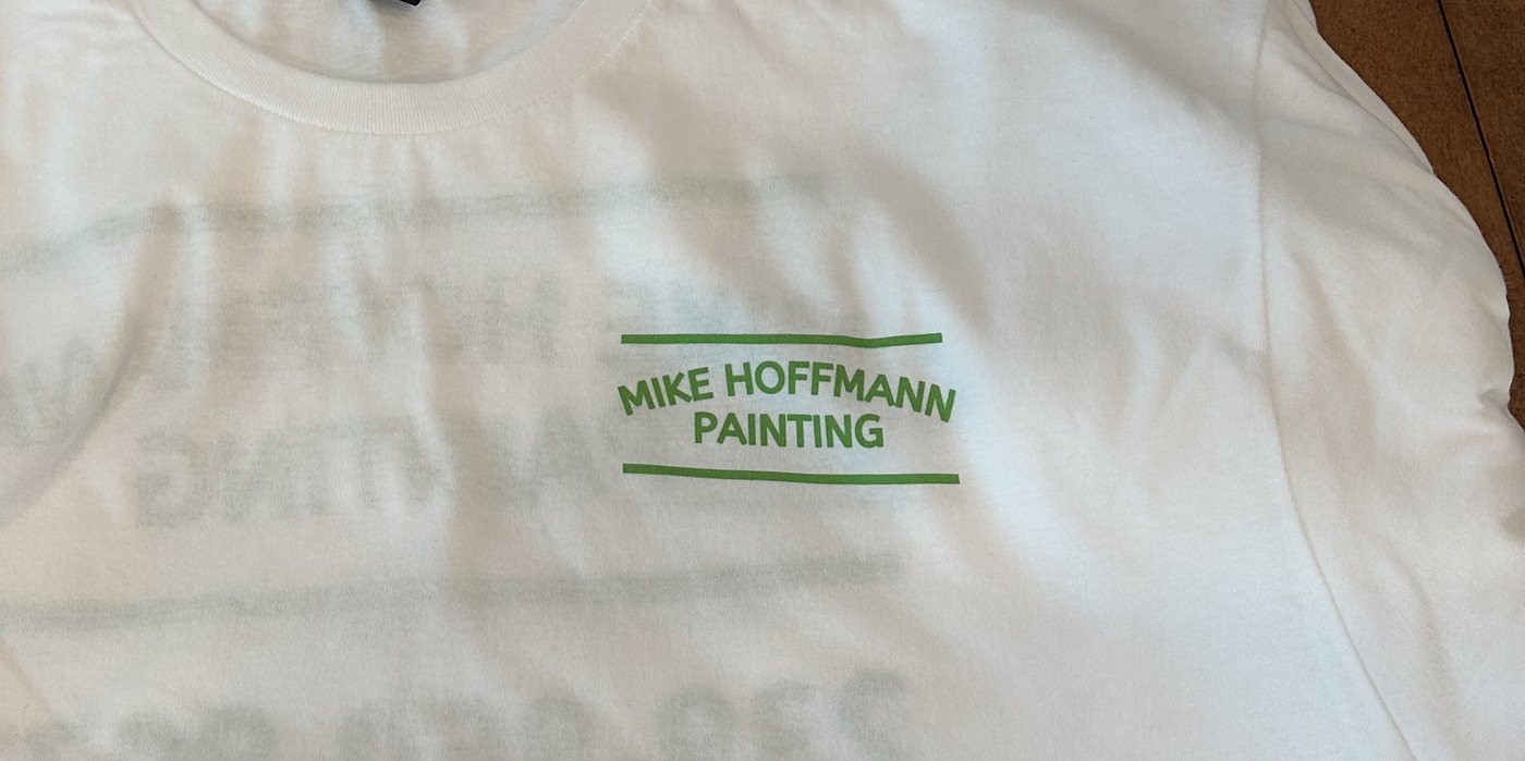 Stacks of white work tees with a 1-color green company logo
