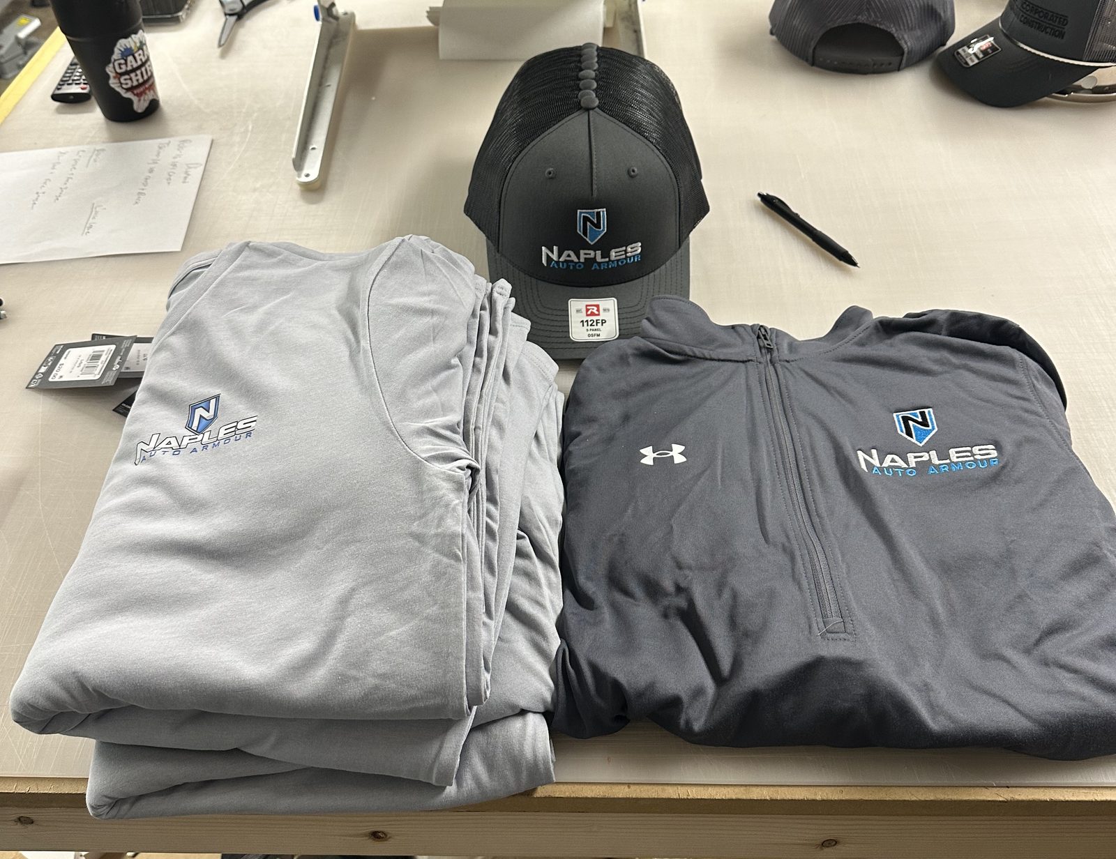 Custom crew kit: printed tees, an embroidered quarter-zip and a trucker hat with the same logo