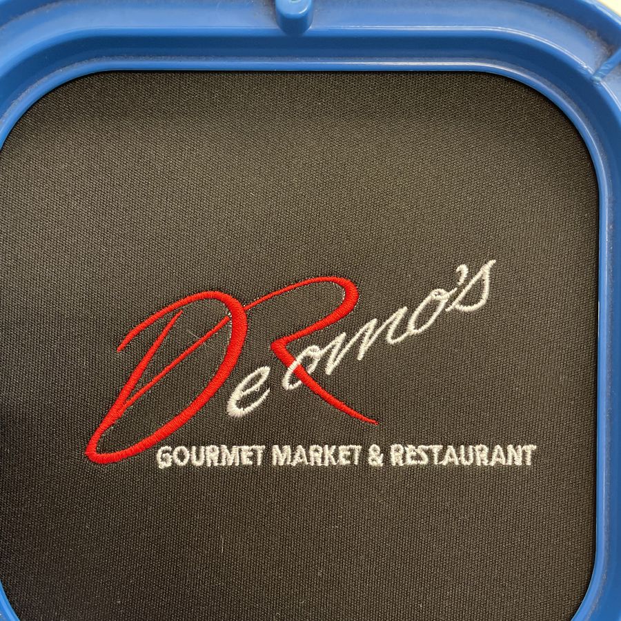 DeRomo's Gourmet Market & Restaurant logo embroidered on a black shirt