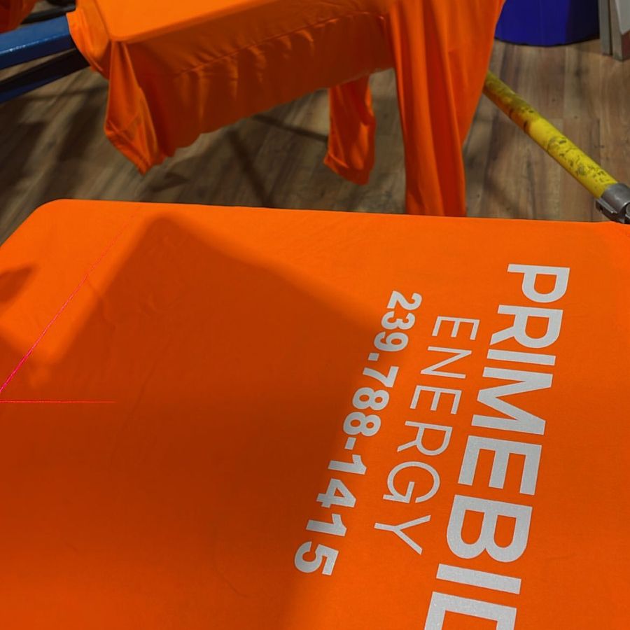 Orange tee printed with the Primebid Energy name and phone number