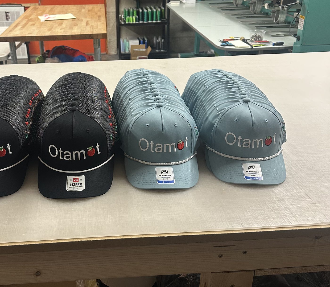 Black and light blue embroidered trucker hats lined up in the shop